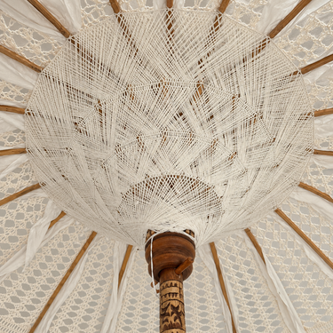 Dettaglio interno macramè geometrico di ombrellone boho chic con palo in legno inciso