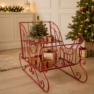 Slitta natalizia in metallo rosso da 100 cm decorata con pacchi regalo e composizione di pino in un elegante ambiente moderno